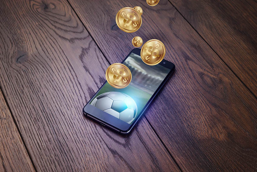 Smartphone on a wooden table. Gold inscription Sports Betting. Bets, sports betting, bookmaker. Mixed media.